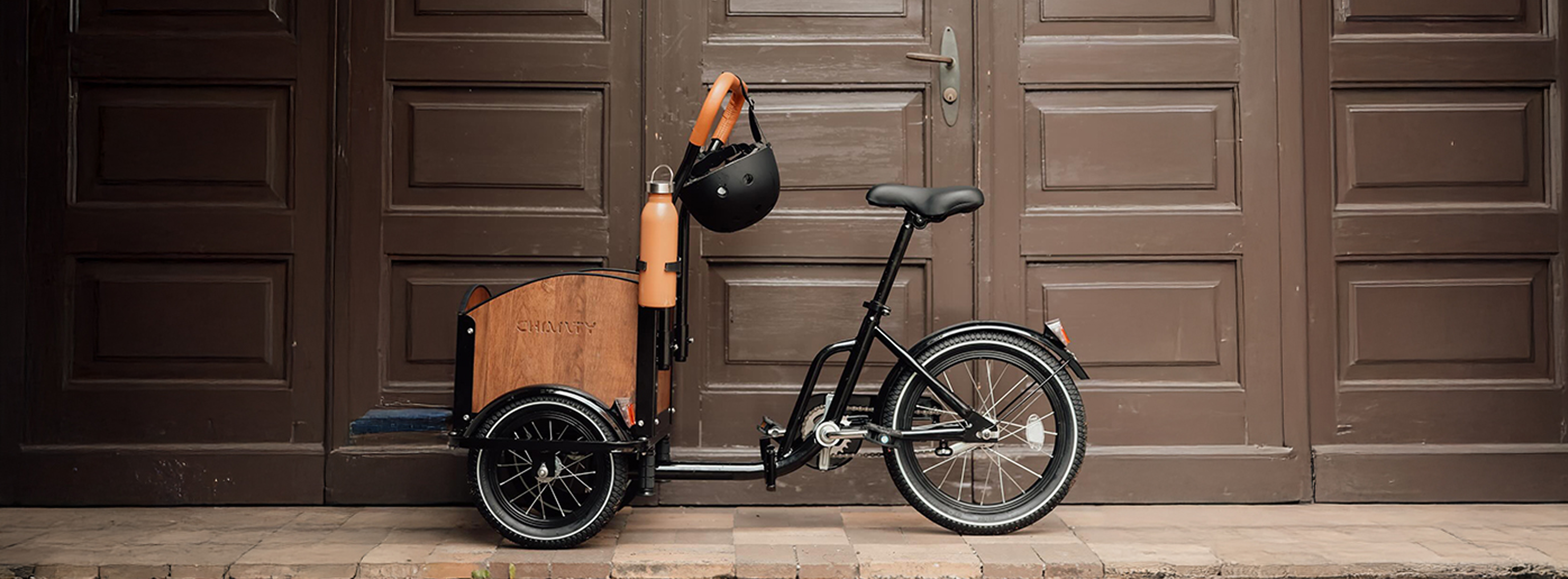 Schwarzes Chanty-Lastenrad vor Holztür.