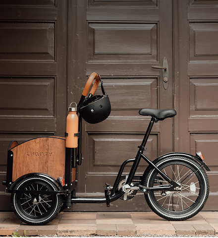 Schwarzes Lastenrad vor Tür.