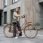 Mädchen mit Fahrrad vor Gebäude.