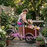 Mädchen belädt rosa Lastenrad mit Rosen.