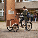 Schüler mit Lastenfahrrad vor Schule.