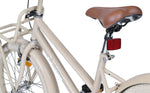 Brauner Fahrradsattel an einem beigefarbenen Rahmen mit rotem Reflektor