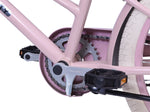 Nahaufnahme des Fahrradantriebs mit Kette, Zahnrad und Pedal am rosa Rahmen